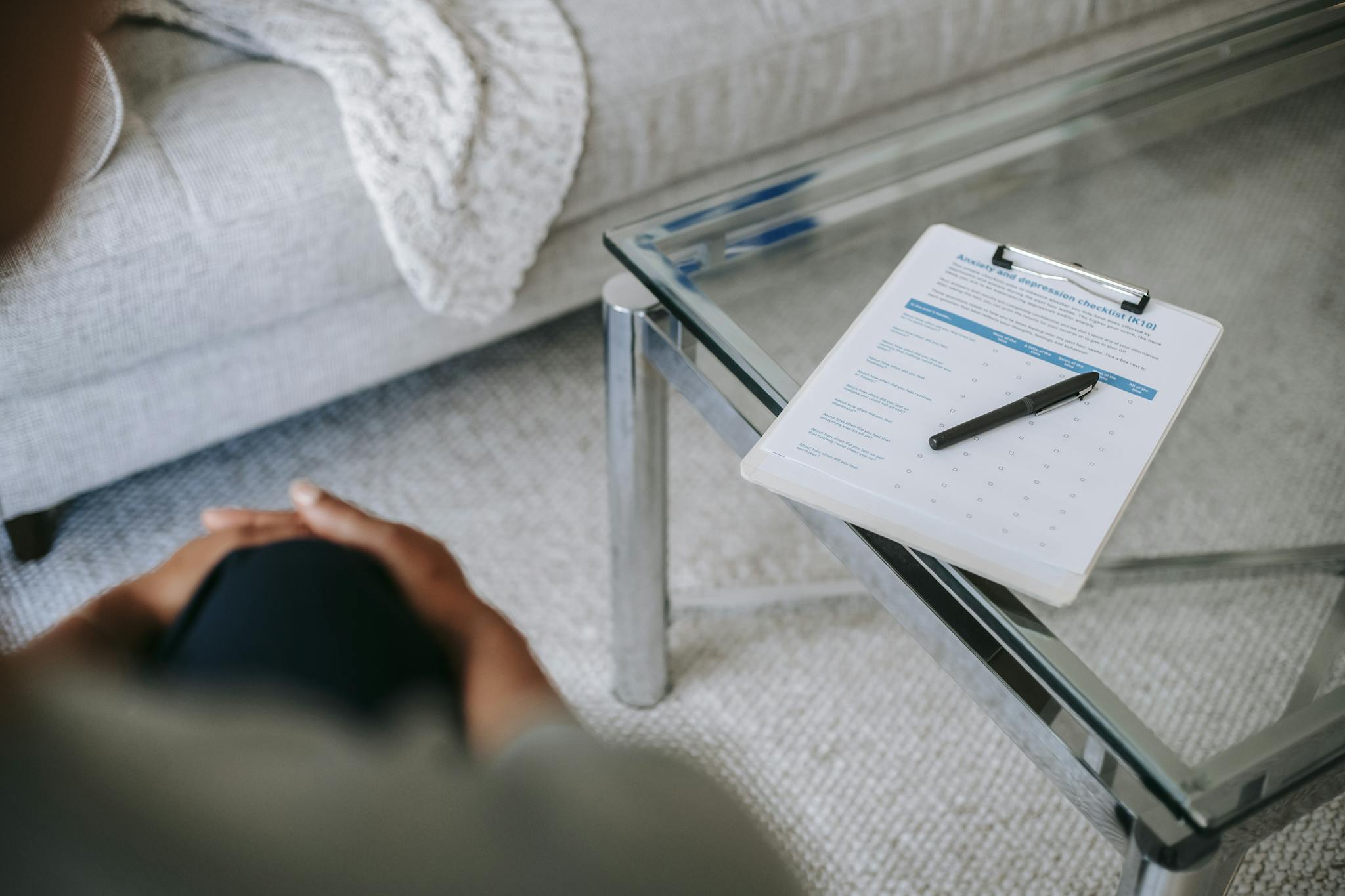 A therapy session setup with a clipboard and anxiety assessment form on a glass table.